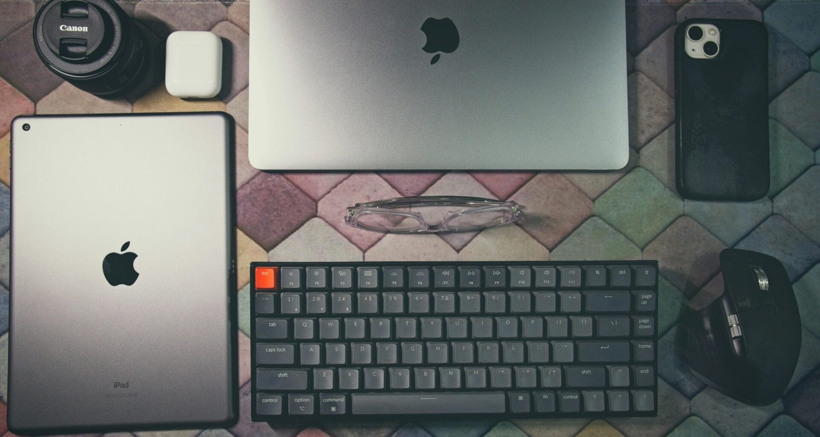 Ein Laptop, eine Tastatur, eine Maus und weiteres Elektronikzubehör stehen ordentlich auf einem Tisch.