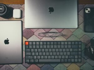 Ein Laptop, eine Tastatur, eine Maus und weiteres Elektronikzubehör stehen ordentlich auf einem Tisch.