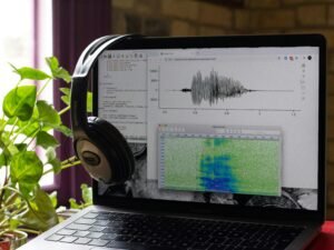 Ein Laptop mit geschlossenen Kopfhörern auf der Tastatur, fotografiert auf einem Schreibtisch als Sinnbild für digitales Arbeiten.