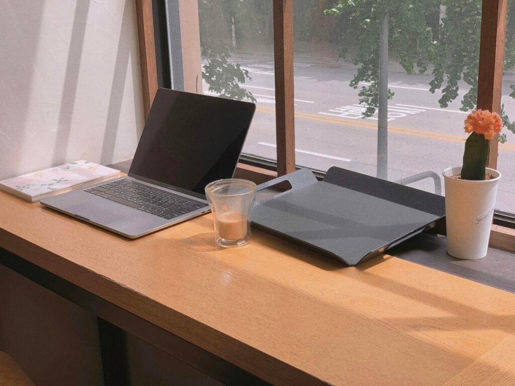 Ein Laptop steht neben einem Glas Wasser auf einem Tisch, perfekte Darstellung eines zeitgemäßen Arbeitsplatzes.