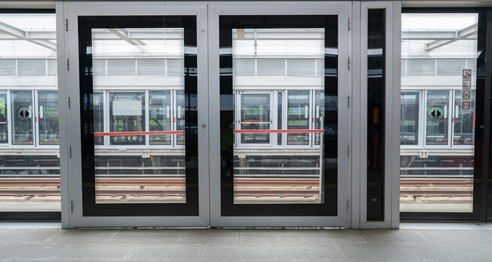 Leere Bahnsteighalle mit zwei geöffneten Türen, modernes Design und klare Linien, geeignet für Themen rund um Mobilität und Infrastruktur