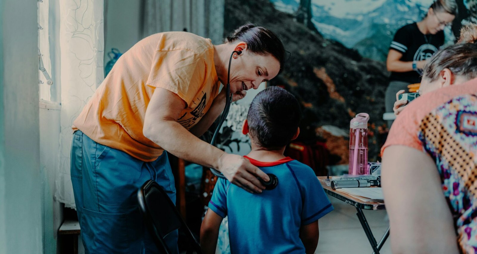 Ein erwachsener Mann steht über einem Jungen, der an einem Tisch sitzt und aufmerksam nach vorne blickt