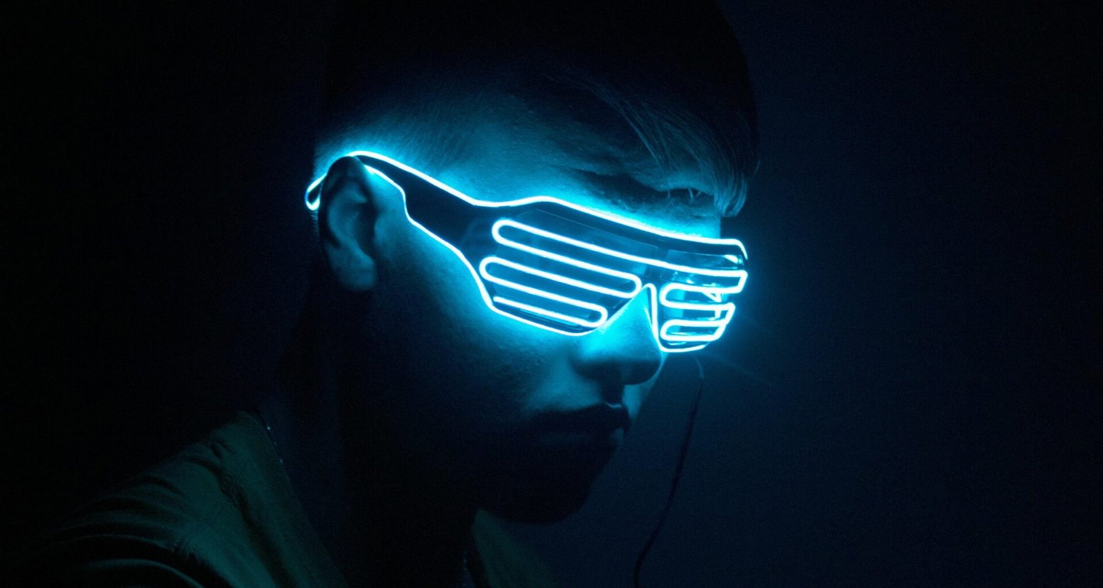 Mann mit leuchtender Neonmaske im dunklen Hintergrund als Sinnbild moderner Technologie und Anonymität