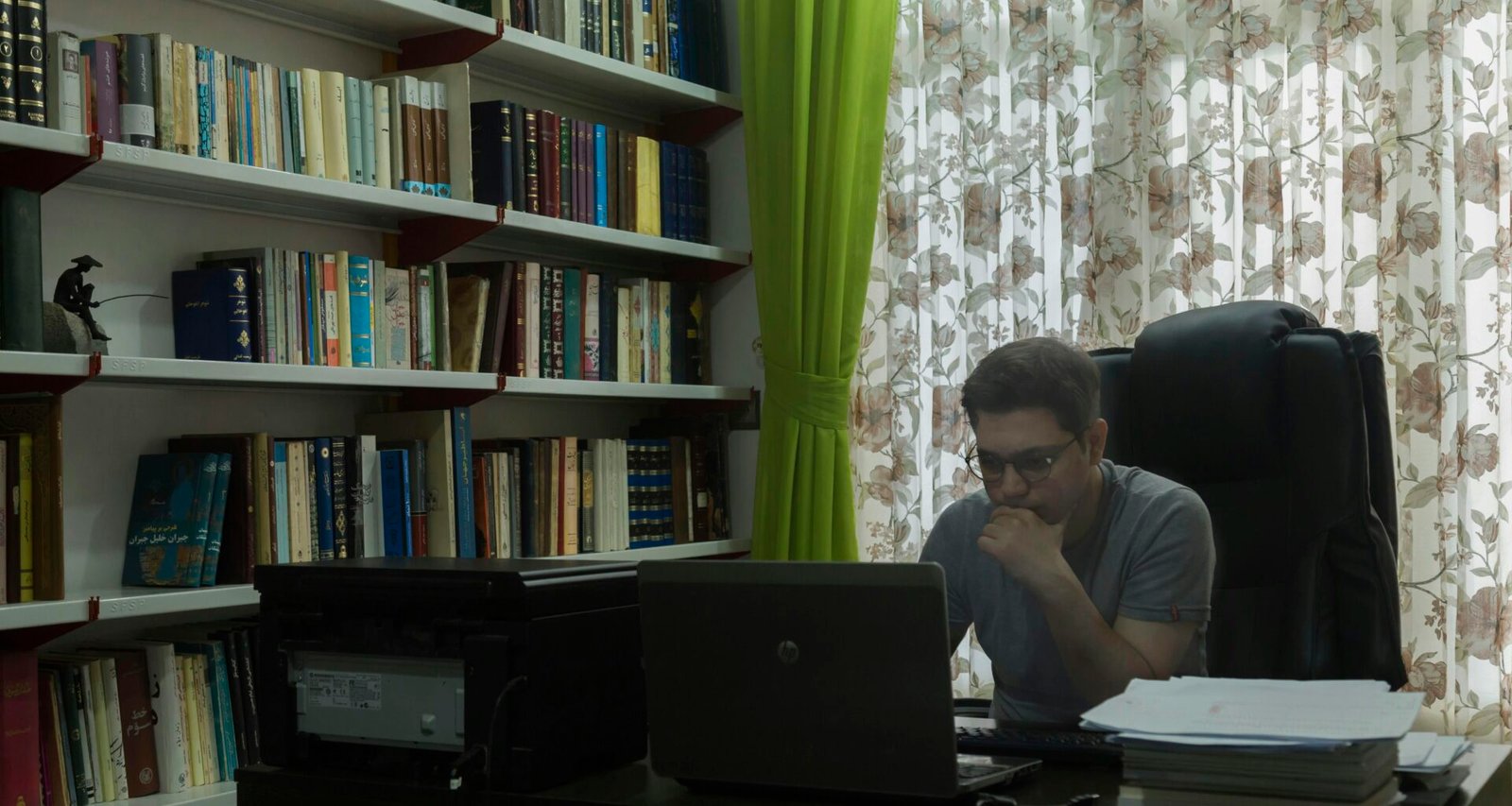 Ein Mann sitzt an einem Schreibtisch vor einem aufgeklappten Laptop und arbeitet konzentriert im Homeoffice.