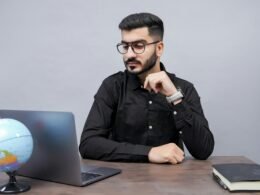 Ein Mann arbeitet an einem Schreibtisch mit einem Laptop und einem Globus, was globale Online-Konnektivität symbolisiert.