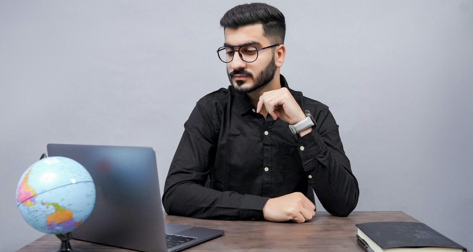 Ein Mann arbeitet an einem Schreibtisch mit einem Laptop und einem Globus, symbolisiert die globale Vernetzung im digitalen Bereich.