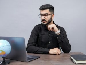 Ein Mann arbeitet an einem Schreibtisch mit einem Laptop und einem Globus, symbolisiert die globale Vernetzung im digitalen Bereich.