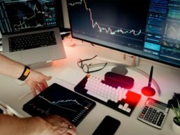 Ein Mann sitzt an einem Schreibtisch mit zwei Monitoren und einem Laptop, ideale Umgebung für digitales Arbeiten.