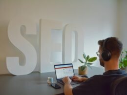 Ein Mann sitzt an einem Tisch und arbeitet an einem aufgeklappten Laptop, geeignet für Themen rund um digitales Arbeiten und Technologie.