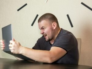 Ein Mann sitzt an einem Schreibtisch und arbeitet an seinem Laptop, konzentriert im modernen Arbeitsumfeld.