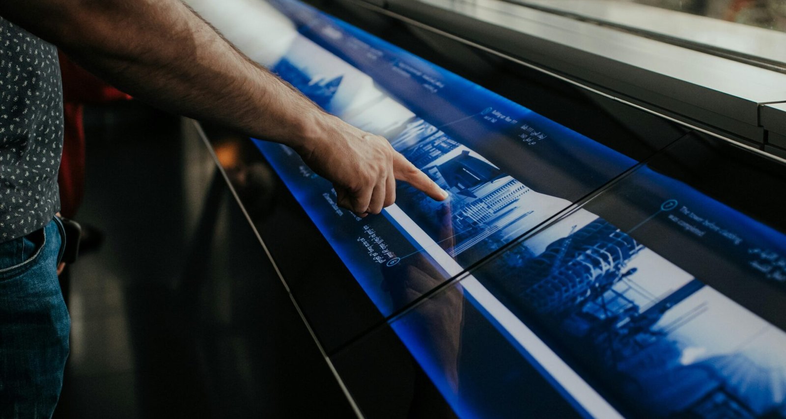 Ein Mann steht vor einem großen Poster und zeigt auf zentrale Elemente, um Informationen anschaulich zu präsentieren.