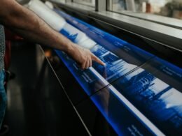 Ein Mann steht vor einem großen Poster und zeigt auf zentrale Elemente, um Informationen anschaulich zu präsentieren.