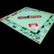 Monopoly-Brettspiel mit Spielfiguren und Karten auf schwarzem Hintergrund, symbolisch für Strategie und Wirtschaft