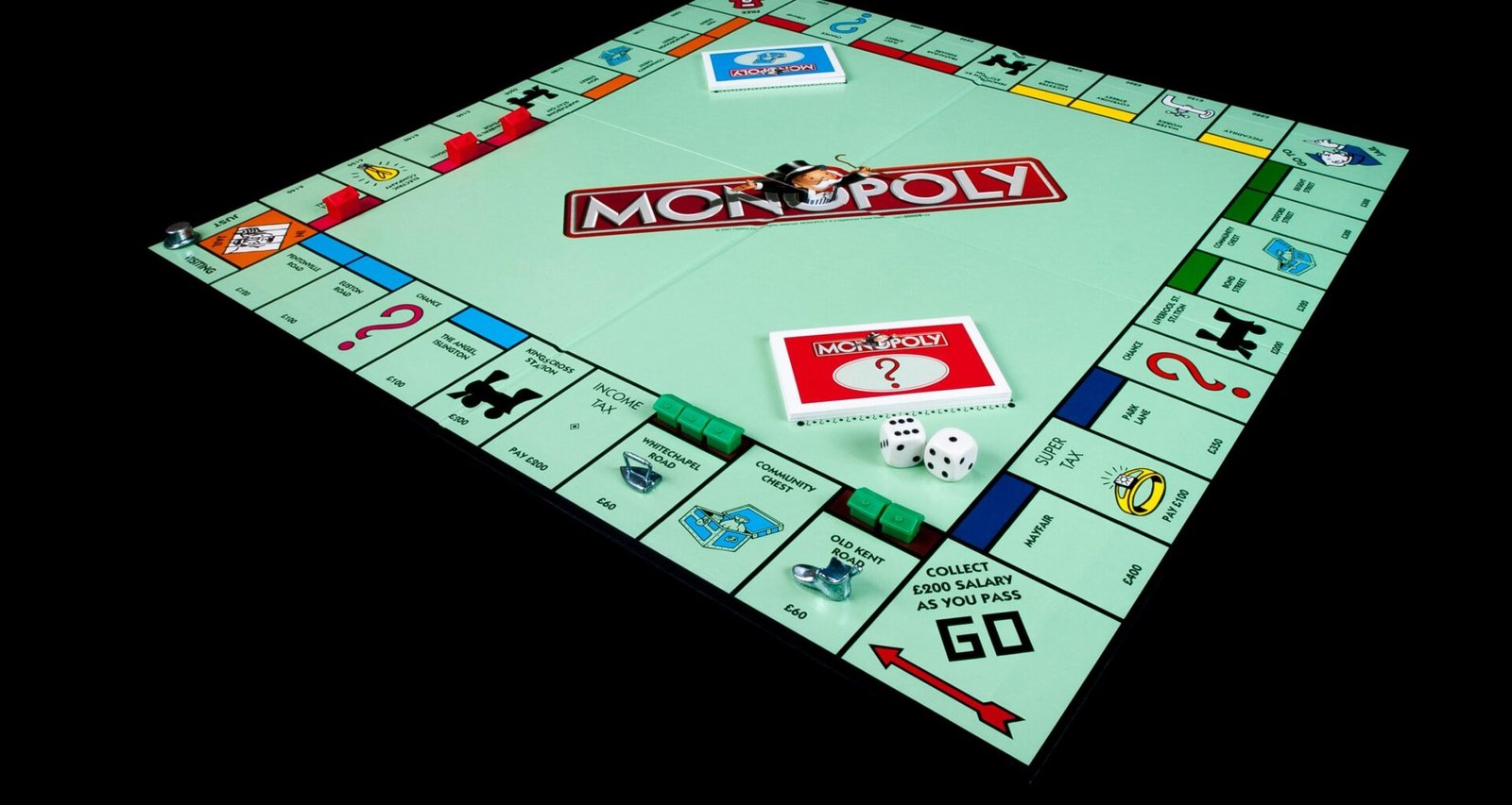Monopoly-Brettspiel mit Spielfiguren und Karten auf schwarzem Hintergrund, symbolisch für Strategie und Wirtschaft