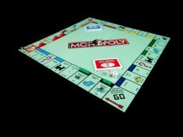 Monopoly-Brettspiel mit Spielfiguren und Karten auf schwarzem Hintergrund, symbolisch für Strategie und Wirtschaft