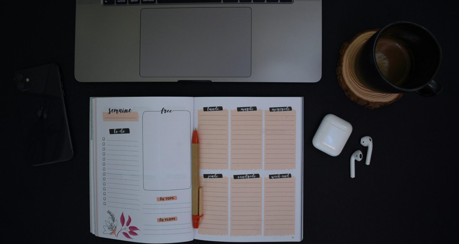 Ein offenes Notizbuch und eine Tasse Kaffee stehen auf einem ordentlich eingerichteten Schreibtisch in moderner Umgebung.