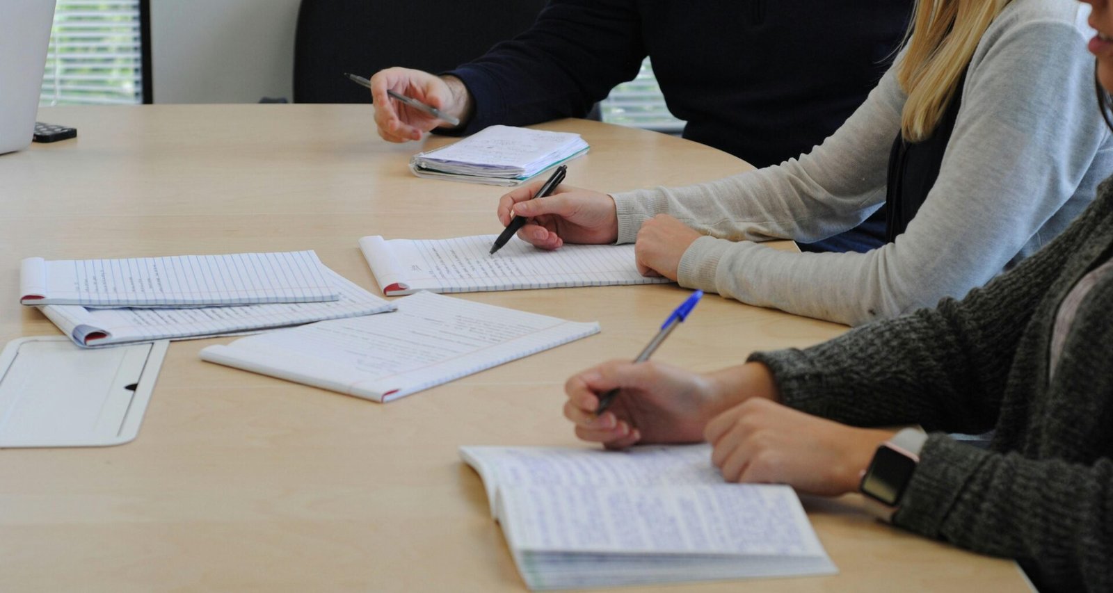 Mehrere Personen sitzen gemeinsam an einem Tisch und besprechen Themen, die Zusammenarbeit und Austausch betreffen.