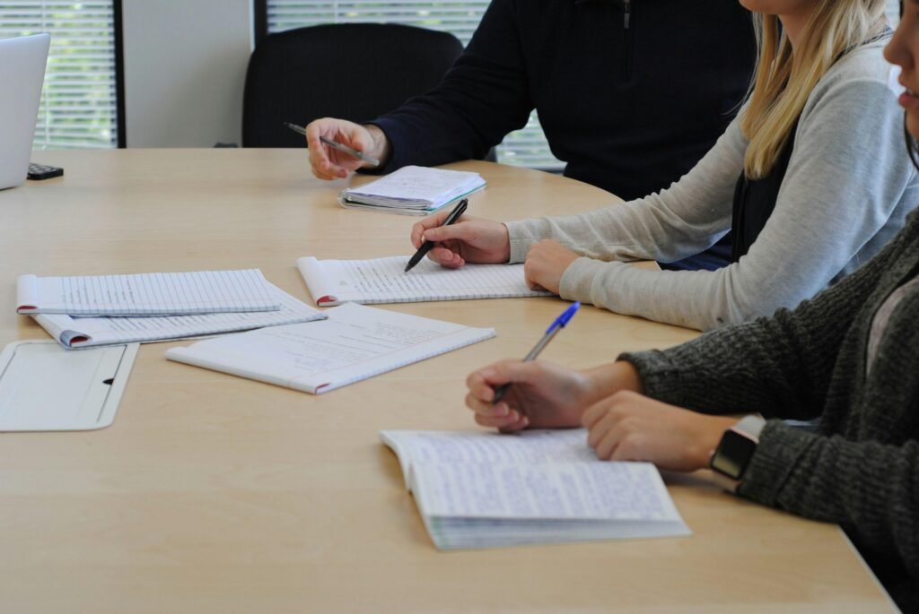 Einige Menschen sitzen zusammen an einem Tisch und unterhalten sich in einer modernen Umgebung während eines Meetings.