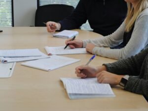 Mehrere Menschen sitzen an einem Tisch und diskutieren miteinander in einem Arbeitsumfeld