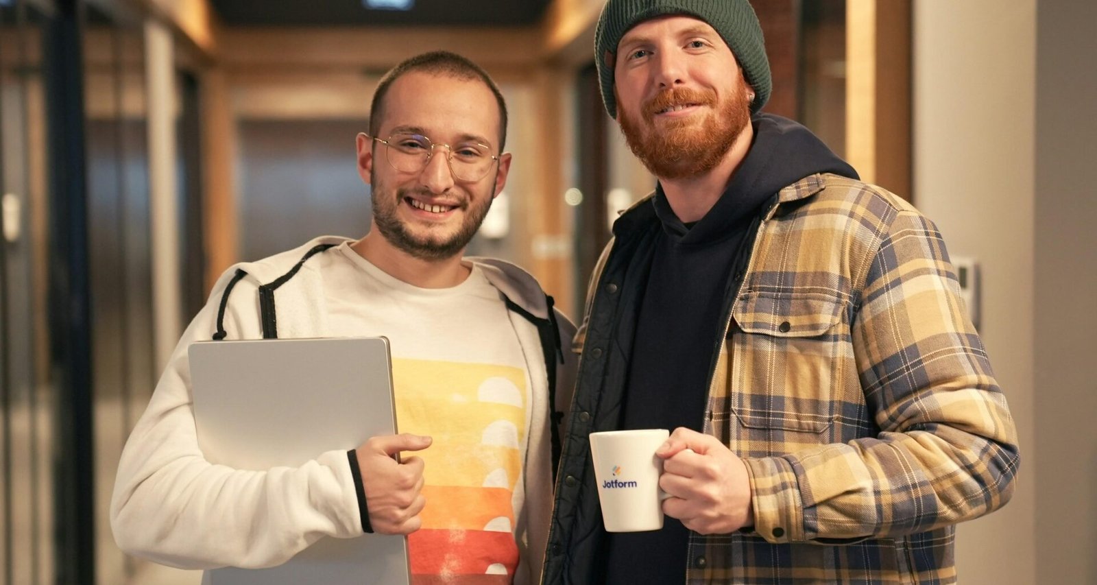 Zwei Männer stehen nebeneinander, Fokus auf Teamarbeit und Kooperation in einem modernen Umfeld