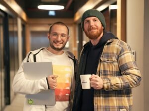 Zwei Männer stehen nebeneinander, Fokus auf Teamarbeit und Kooperation in einem modernen Umfeld