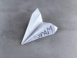 Papierflieger mit dem handgeschriebenen Wort Spam als Sinnbild für unerwünschte E-Mail-Kommunikation