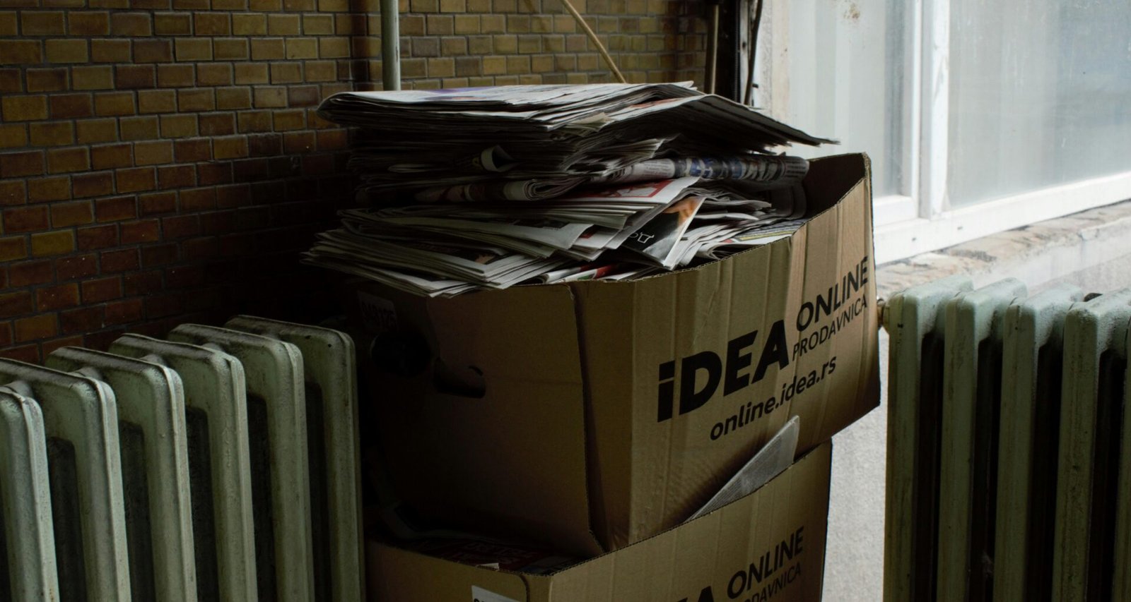 Kartonbox auf einem weißen Heizkörper platziert, neutraler Hintergrund, geeignet für Artikel zu Versand oder Lagerung