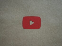 Roter Play-Button liegt auf einem weißen Stück Papier und steht als Symbol für Video-Inhalte auf Websites.
