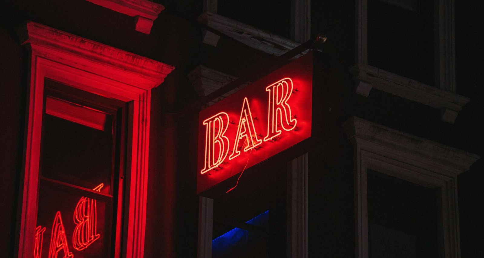 Rotes, beleuchtetes Bar-Schild leuchtet in der Dunkelheit, fotografiert von Jose Marroquin – urbanes Nachtbild
