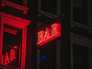 Rotes, beleuchtetes Bar-Schild leuchtet in der Dunkelheit, fotografiert von Jose Marroquin – urbanes Nachtbild