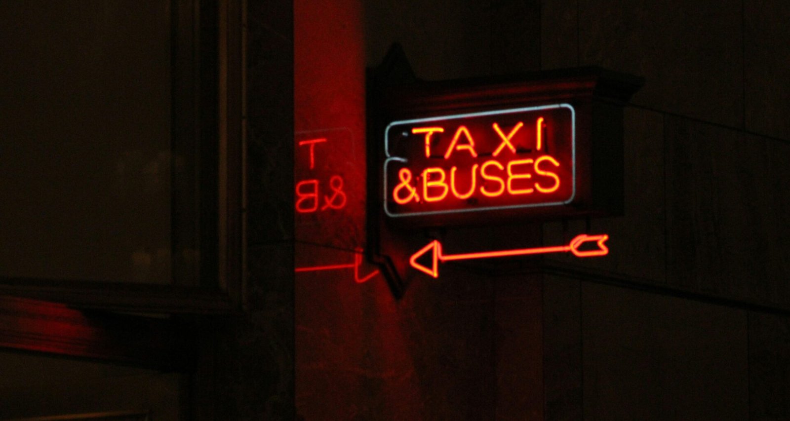 Rotes Taxi-Schild montiert an der Seite eines Stadthauses, deutlicher Blick auf die Leuchtreklame bei Tageslicht