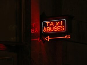 Rotes Taxi-Schild montiert an der Seite eines Stadthauses, deutlicher Blick auf die Leuchtreklame bei Tageslicht