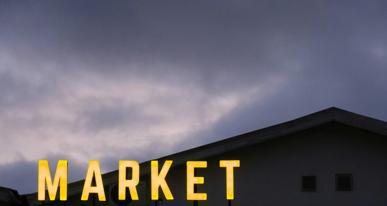 Ein Schild mit der Aufschrift Market auf dem Dach eines modernen Gebäudes, aufgenommen als Symbol für Marktplätze.