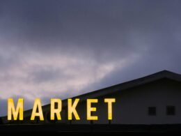 Ein Schild mit der Aufschrift Market auf dem Dach eines modernen Gebäudes, aufgenommen als Symbol für Marktplätze.