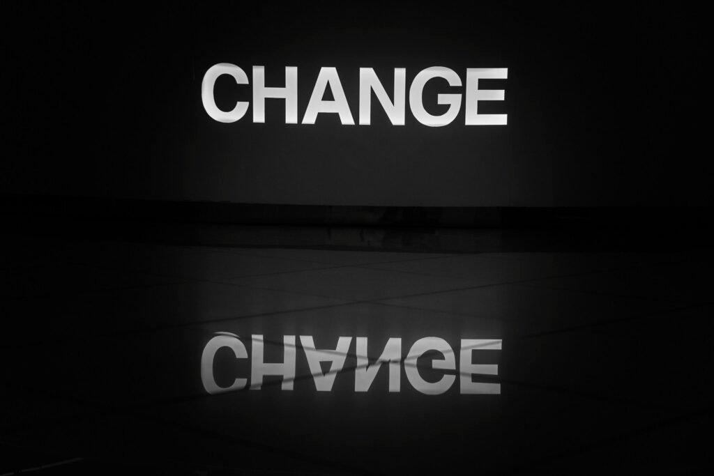 Schwarz-weiß fotografiertes Wort ‚change‘ auf einer Oberfläche, symbolisiert Wandel und Anpassung im digitalen Bereich.