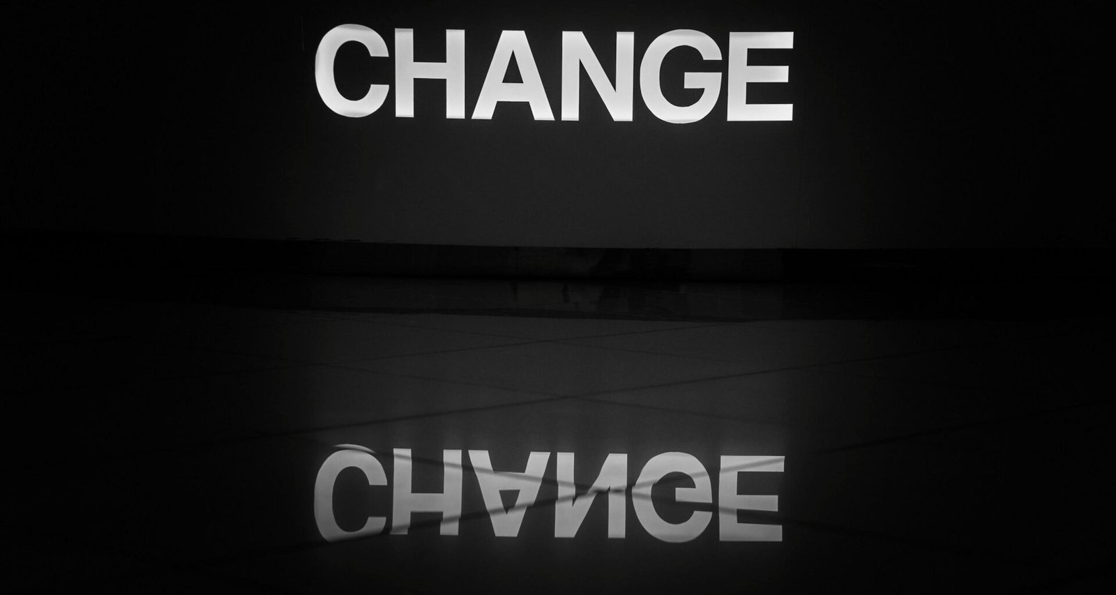 Schwarz-weiß fotografiertes Wort ‚change‘ auf einer Oberfläche, symbolisiert Wandel und Anpassung im digitalen Bereich.