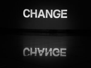 Schwarz-weiß fotografiertes Wort ‚change‘ auf einer Oberfläche, symbolisiert Wandel und Anpassung im digitalen Bereich.