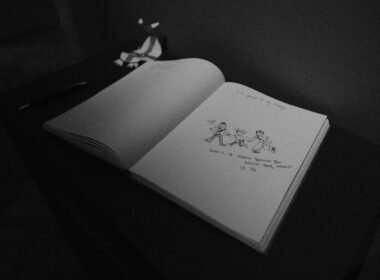 Schwarz-weißes Foto eines aufgeschlagenen Buches auf einer ebenen Fläche, aufgenommen von Dominic Kurniawan Suryaputra