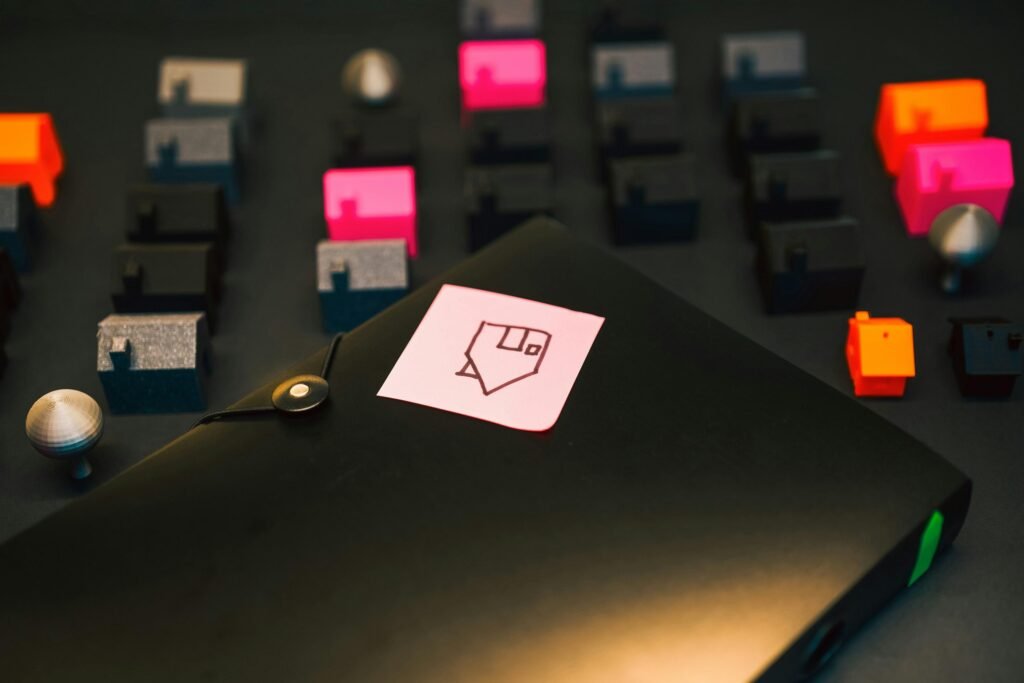 Schwarzer Aktenordner mit aufgeklebter gelber Haftnotiz auf einem grauen Hintergrund, geeignet für Büroorganisation.