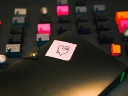 Schwarzer Aktenordner mit aufgeklebter gelber Haftnotiz auf einem grauen Hintergrund, geeignet für Büroorganisation.