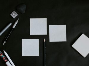 Schwarzer Tisch, auf dem mehrere weiße Karten und ein Bleistift ordentlich arrangiert liegen