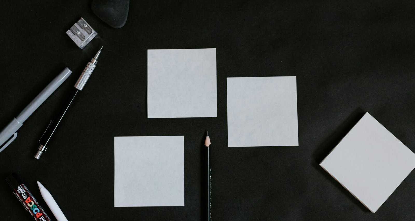 Schwarzer Tisch, darauf weiße Karten und ein Bleistift, ideal für Organisation und Planung im Arbeitsalltag