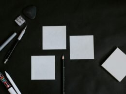 Schwarzer Tisch, darauf weiße Karten und ein Bleistift, ideal für Organisation und Planung im Arbeitsalltag