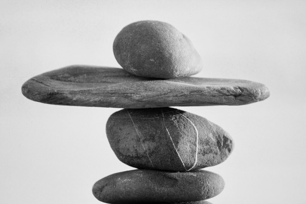 Mehrere übereinandergestapelte Steine vor unscharfem Hintergrund, Symbol für Balance in der Natur.