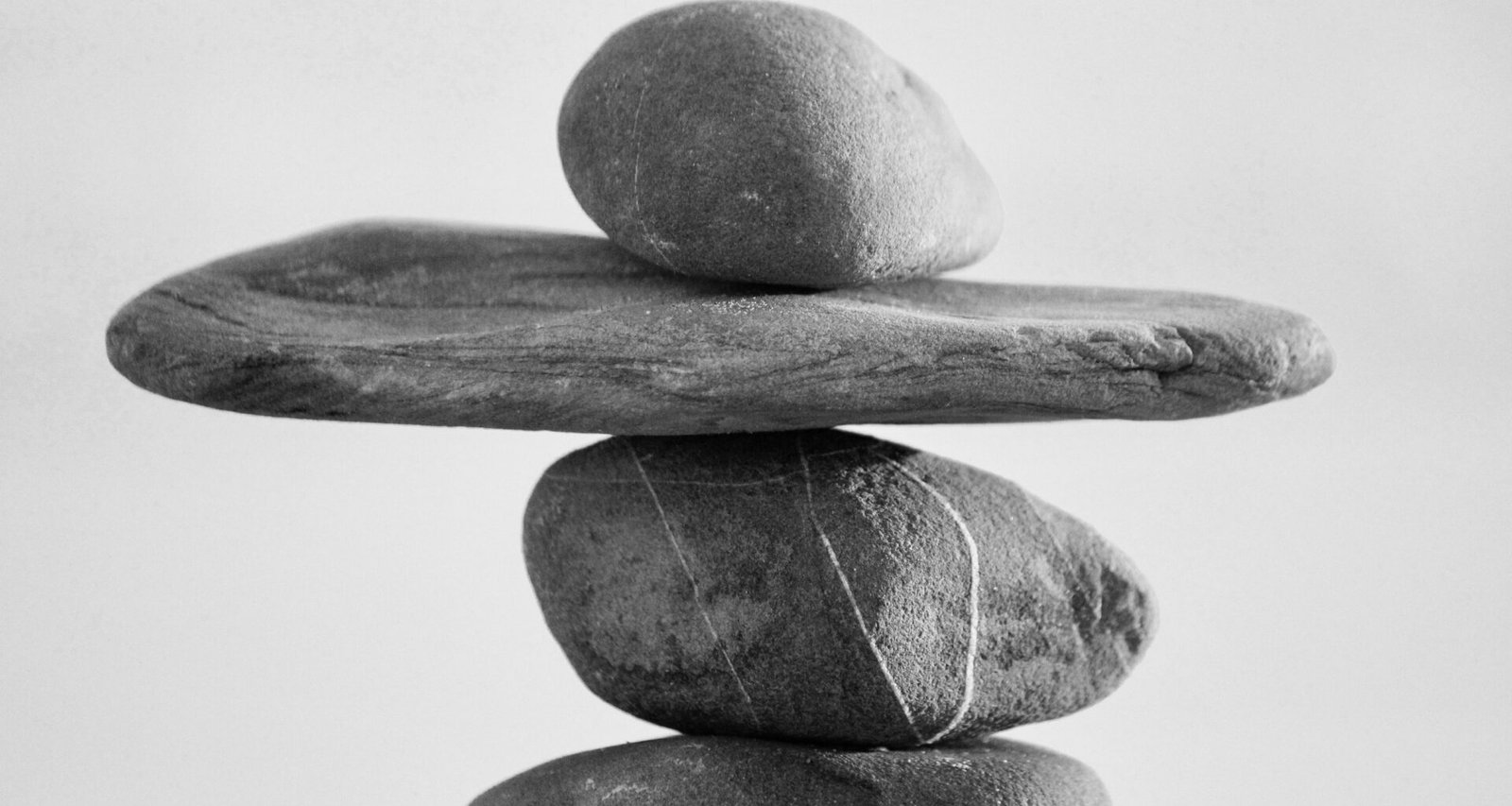 Mehrere übereinandergestapelte Steine vor unscharfem Hintergrund, Symbol für Balance in der Natur.