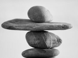 Mehrere übereinandergestapelte Steine vor unscharfem Hintergrund, Symbol für Balance in der Natur.