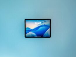 Tablet mit abstrakter blauer Tapete als Display, gehalten in Nahaufnahme, passend für Technik- und Digitalthemen