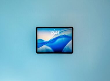 Tablet mit abstrakter blauer Tapete als Display, gehalten in Nahaufnahme, passend für Technik- und Digitalthemen