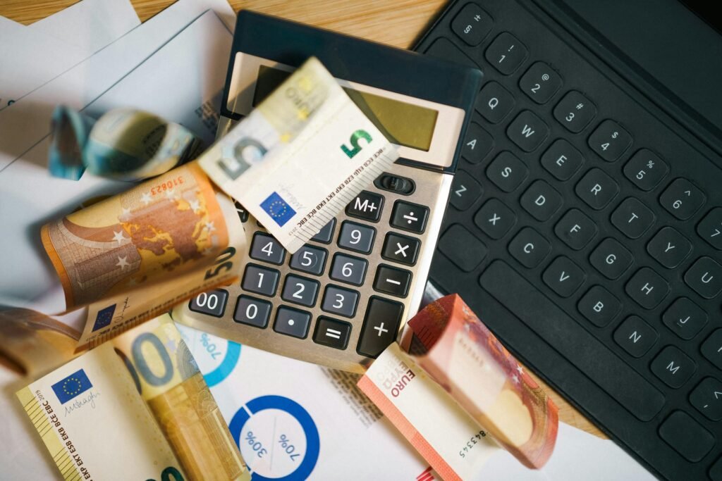 Ein Taschenrechner liegt auf einer Vielzahl von Geldscheinen und steht für finanzielle Kalkulationen und Budgetplanung.