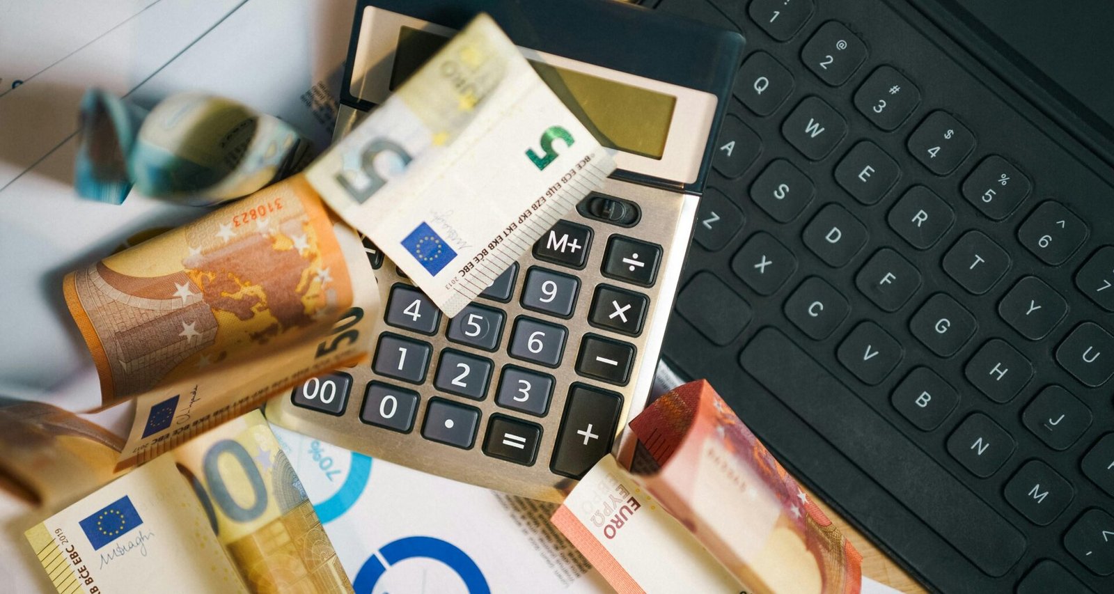 Ein Taschenrechner liegt auf einer Vielzahl von Geldscheinen und steht für finanzielle Kalkulationen und Budgetplanung.